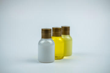 Photo of three bottles near of shampoo in back a white wallpaper