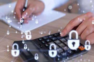 A businessman computing probability of risks in cyber security protection using calculator. Padlock Hologram icons over the working desk. Formal wear.