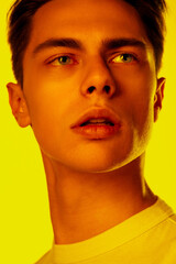 Lips. Handsome caucasian man's portrait isolated on orange studio background in neon, monochrome. Beautiful male model. Concept of human emotions, facial expression, sales, ad, fashion and beauty.