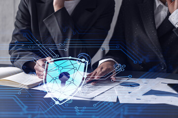 Two businesswomen working on the project to protect cyber security of international company. Padlock Hologram icons over the table with documents.