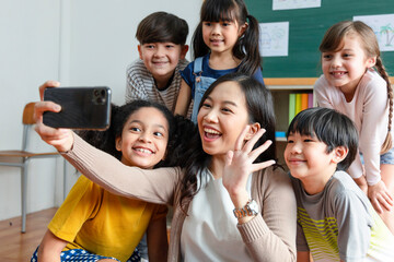 teachers use smartphones to take selfies with a group of students.