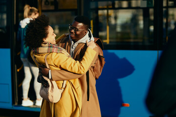 Happy African American couple meeting at bus station.
