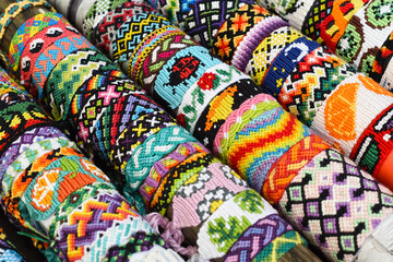 Many tied woven DIY friendship bracelets handmade of embroidery floss. Alpha and normal patterns