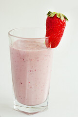 Milk strawberry smoothie made from fresh fruits on a light background. Strawberry cocktail. A glass of delicious milk cocktail with strawberries.