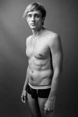 Young handsome man with blond hair shirtless against gray background