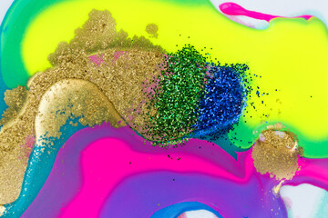 Blue, green and gold glitter on fluorescent liquid ink background.