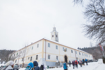 Group of hikers et orthodox monastery Velika Remeta on the mountain Fru&scaron;ka Gora in northern Serbia. Winter snowy day.