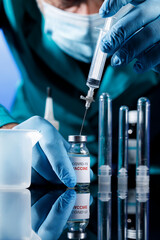 dettaglio delle mani di un Medico con protezioni e guanti in lattice che preleva il vaccino...