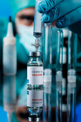 Medico con protezioni mediche e guanti in lattice preleva del il  vaccino anti-covid con una...
