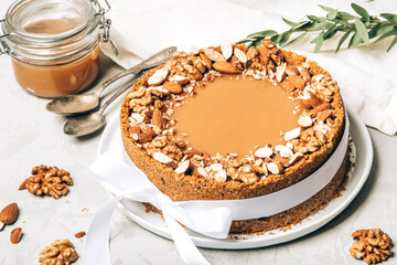 Cheesecake with salted caramel and nuts on a gray background.