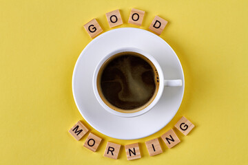 Good morning concept. Empty white cup and good morning wish made of wooden cubes.