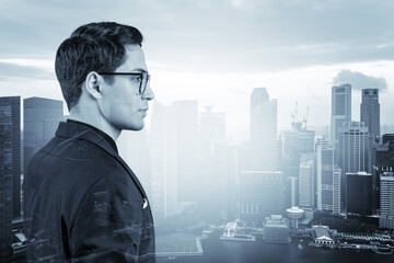 Young handsome businessman in suit and glasses dreaming about new career opportunities after MBA graduation. Singapore on background. Double exposure.