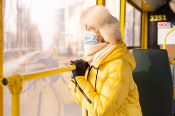 Bright sunny portrait of a young woman in warm clothes in a city bus on a winter day