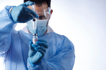 Medico con mascherina chirurgica e guanti in lattice preleva il vaccino anti-covid da una fiala di...