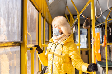 Fototapeta na wymiar Bright sunny portrait of a young woman in warm clothes in a city bus on a winter day