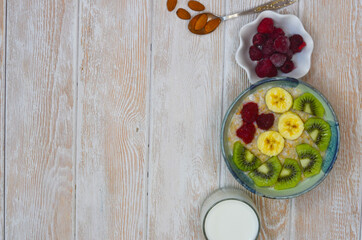 Healthy food for breakfast top view flat lay. Oatmeal porridge with milk, kiwi and banana fruit and raspberry