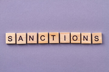 Sanctions word made of wooden cubes. Isolated on purple background.