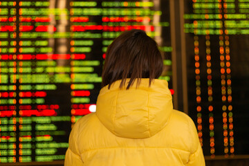 Woman passenger at railway station, board with departure routes on background