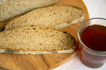 Bread and tea for breakfast. Slices of bread and a glass of strong tea close-up. Fresh aromatic rye bread, cut into pieces.