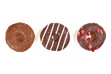 Three chocolate glazed cookies with different toppics in a row on white background