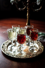 Different kinds of vermouth in small liqueur glasses on a silver tray, a beautuful old candlestick