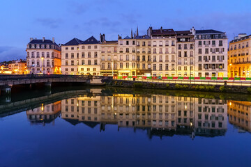 Fototapeta na wymiar City of Bayonne in France at night with houses of typical architecture and reflections on the Adur River 