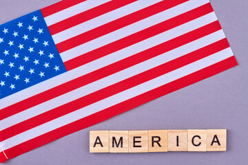 Flag of United States of America. Wooden alphabet blocks with letters isolated on violet background.
