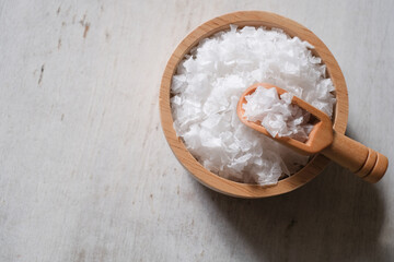 Flower of salt, is a salt that forms as a thin, delicate crust on the surface of seawater in the wooden scoop and wooden bowl on wooden background.