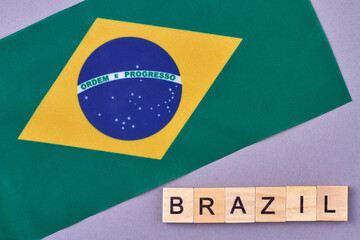 Obraz premium National flag of Brazil. Wooden alphabet blocks with letters isolated on violet background.