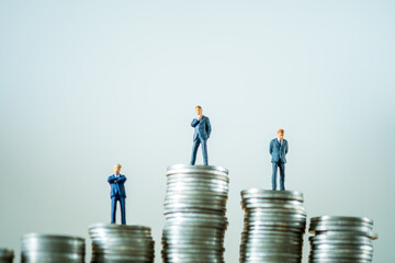 Miniature people businessman on top of stacks coins in money communication on white background