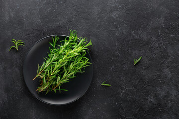 Obraz na płótnie Canvas Rosemary herb on a plate on a black background.