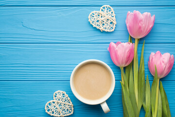 Flat lay close up top view overhead photo of beautiful fashionable pastel color tulips with rattan hearts isolated on wooden bright blue desk