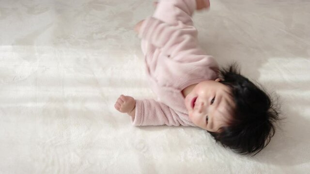 寝返りを失敗する赤ちゃん（0歳、生後6カ月、女の子、日本人）