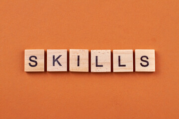 Skills and development concept. Skills text on wooden cubes isolated on orange background.