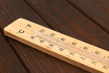 Close-up photo of household alcohol thermometer showing temperature in degrees Celsius on a wooden background. Close-up, selective focus