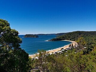Beautiful view of a deep blue sea with white sandy beach, small island and deep blue sky in the background, Mount Ettalong Lookout, Pearl Beach, Brisbane Water National Park, New South Wales, Australi