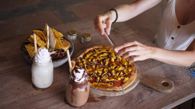 Top view of hands taking picture of vegan lunch consisted of pizza, nachos and milkshakes in glass jar served on wooden table . Food blogging concept