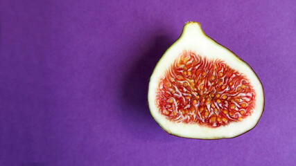 half of a ripe juicy fig with a red center on a lilac background top view . healthy sweet fruits