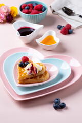 Heart shaped  belgian waffles with Ice-cream and berries on pink background. Tasty breakfast. Close-up.