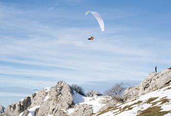 Paraglider flying over the mountains in winter