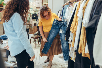 Shop assisting helping shopper in clothing store