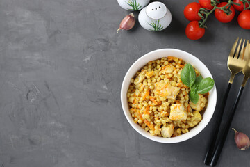 Homemade ptitim pasta with chicken and vegetables on dark gray table. Horizontal format.