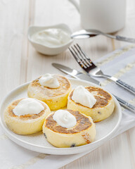 still life with cottage cheese pancakes with sour cream on white table