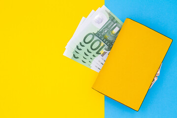 Close-up of yellow wallet with 100 Euro banknotes on a colored background