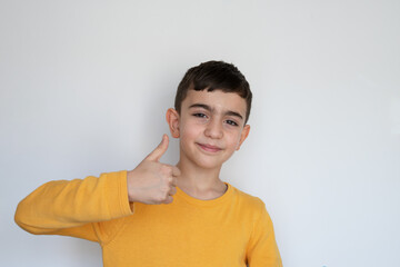 positive child shows a hand gesture of an agreement, like, approval neutral background. boy showing thumbs up and looking at camera, isolated. Turkish boy. © Studio Roux