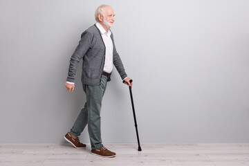 Full size profile photo of old man go with wand wear dark sweater trousers isolated on grey wall