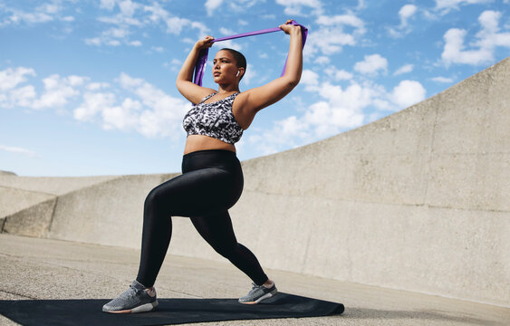 Plus size woman exercising with resistance band