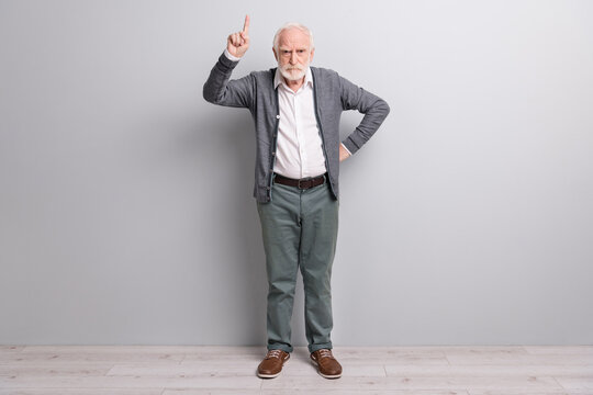 Full size photo of old sad man finger up wear dark sweater trousers boots isolated on grey wall