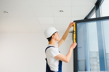 Construction worker installing window in house