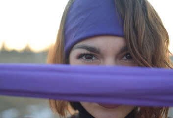 Young Caucasian woman looks straight ahead through a purple scarf. Concept of struggle for women's rights, feminism.